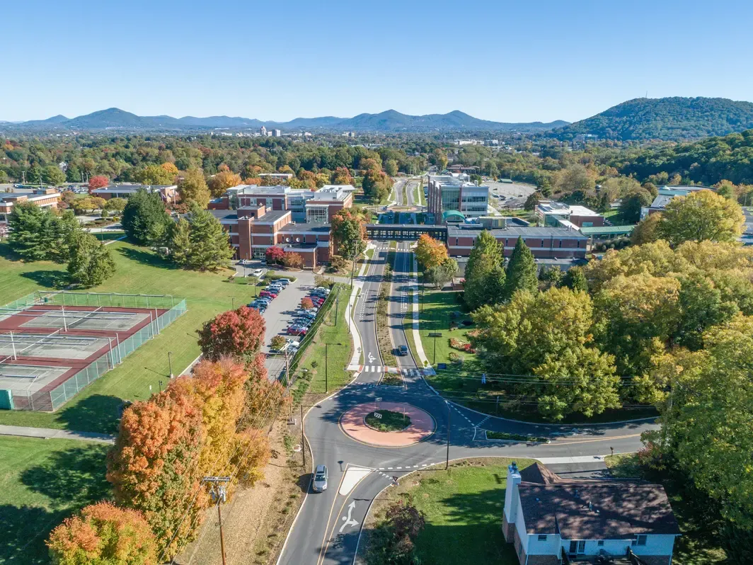 Aerial view of a suburban area with vibrant autumn foliage and a roundabout.